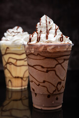 Chocolate milkshake served in a clear glass on a dark background. Isolated drink