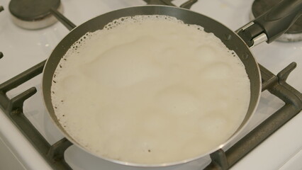 Cooking delicious batter in a frying pan placed on a gas stove for a tasty meal preparation
