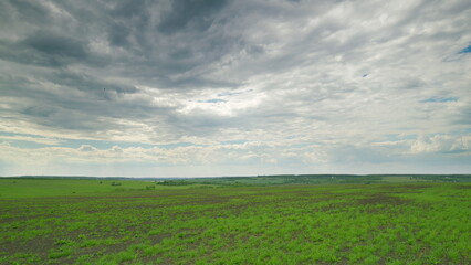 Obraz premium The Expansive Green Fields Stretching Beneath a Dramatic and Majestic Cloudy Sky Time lapse.