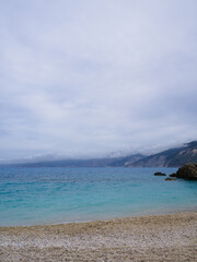 Moody landscape of a deserted beach on a cloudy day with dramatic storm clouds and calm sea, capturing quiet solitude in nature.