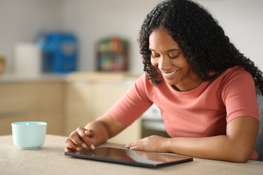Happy black woman checking a digital tablet in the kitchen
