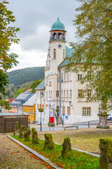 Naklejka premium Jachymov's Town Hall stands prominently with its unique clock tower and green dome, surrounded by charming pathways and autumn foliage, reflecting the town's rich history and culture.