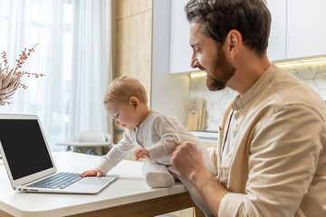 Fototapeta premium Young father with his little son at the laptop at home