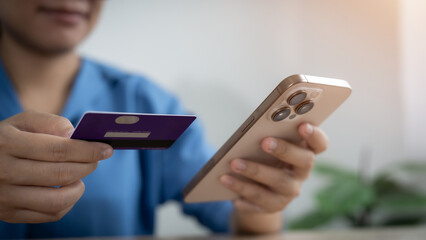 A woman is using her phone to pay for something with a credit card. She is smiling as she does this