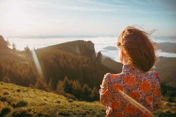 A lady admires the sunrise in the mountains. The fog is lifted from the mountains. The light shines...