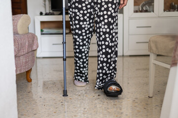 Senior woman, navigating her home with crutches and a walking cast after undergoing foot surgery,...