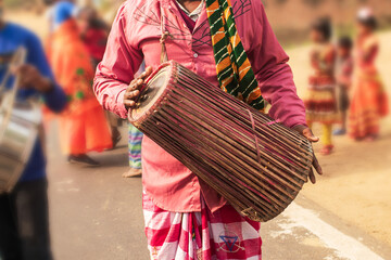 A traditionally dressed man joyfully plays a drum, locally known as the madal. His colourful attire...