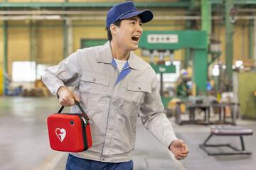  工場でAEDを持って駆けつける男性作業員