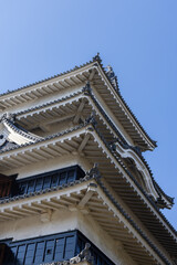 Curved tiled eaves and layered rooftops of Matsumoto Castle in Nagano show traditional defensive design with hidden floor and sharp facade contrasts