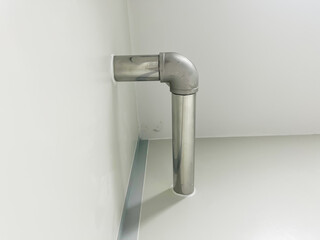 Stainless steel plumbing pipe system installed in clean white interior corner, showcasing modern industrial design, functionality. Ideal for engineering, construction, plumbing system concepts