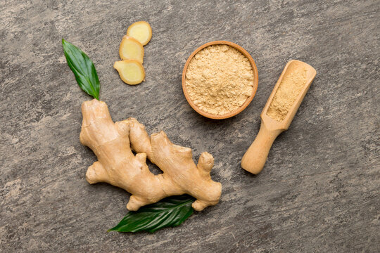 Finely dry Ginger powder in bowl with green leaves isolated on colored background. top view flat lay