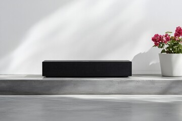 Sleek black soundbar on a concrete ledge, against a white wall