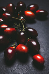 Fresh organic black tomatoes on dark background, ready for healthy food preparation in the kitchen