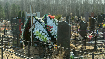 Artificial flowers and a lit candle lamp on a cemetery grave symbolize memory, faith, and hope for...