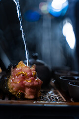 The Gongfu tea ritual features clay teacups, a teapot, and an ornate tea pet. Gongfu tea ceremony with clay cups and a detailed tea tray captured in warm lighting.