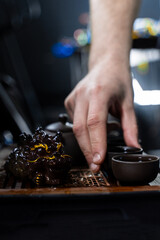 Gongfu tea ceremony with clay cups and a detailed tea tray captured in warm lighting. The Gongfu...