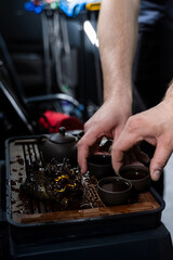 Gongfu tea ceremony with clay cups and a detailed tea tray captured in warm lighting. The Gongfu...