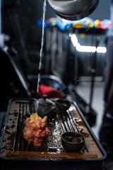 Hot water is poured onto a vibrant dragon tea pet during a Gongfu tea ceremony. Water flows onto a dragon-shaped tea sculpture in a Gongfu tea setting.