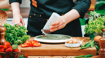 Chef skillfully prepares healthy salad, drops sauce on plate, using fresh vegetables and vibrant...