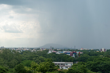 View of lush green Madurai cityscape with distant hills and approaching rain clouds in the sky