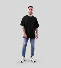 Fototapeta premium Mockup of black oversized t-shirt on bearded guy in jeans, sneakers, full length front view, isolated on background.