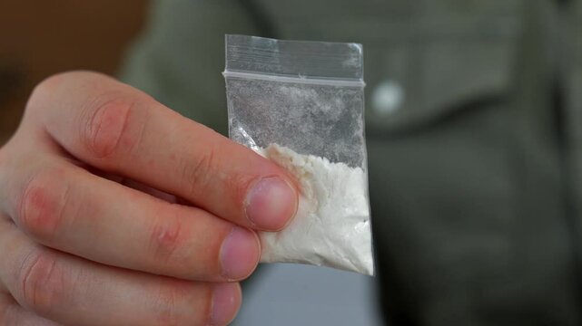 A man holds a package of geraine in his hands.
A man holds a zip bag with a narcotic substance.
Drug trafficking.
Cocoin, heroin, drug addict, trade, drug business