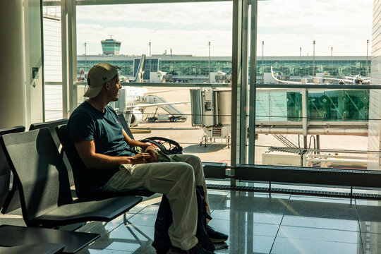 Tourist waiting for departure sitting in airport lounge looking at airplane through window