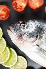 Fresh Whole Dorado Sea Bream Fish with Cut Limes and Tomatoes