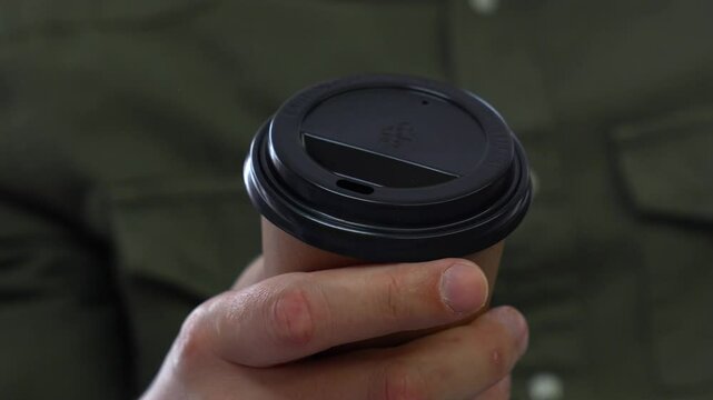 Close-up of a coffee glass in hands.
Man holding cortona disposable glass with hot takeaway drink