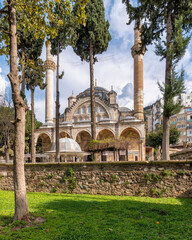Muradiye Mosque in Manisa, Turkey. Historic Ottoman architecture with minarets, dome, and arches, surrounded by trees and a garden