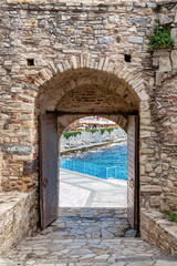 The gate of Kusadasi Castle opening to the Aegean Sea with a blue railing, in Izmir, Turkey, daytime