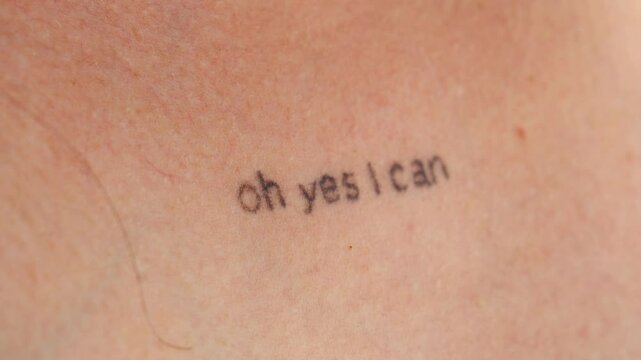 A graphic design on the body of a young girl.
Tattoo on a woman's chest.
The inscription on the chest is OH YES I CAN close-up.
Stylish and modern tattoo in a minimalist style