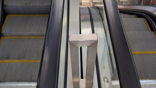 View of escalator steps and side panels in a modern shopping mall during busy afternoon hours
