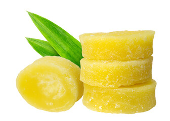 A set of four golden palm sugar chunks, three piled up, one off to the side, with a couple of leafy greens for contrast.