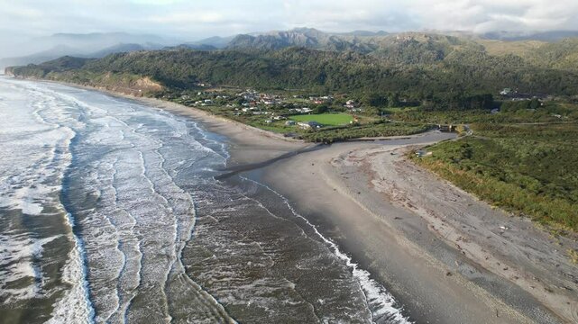 Waves Splashing On Sandy Beach Of Rapahoe With Davy Creek Mouth. West Coast Of South Island, New Zealand. aerial pullback shot
