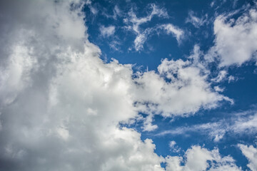 White fluffy clouds scattered across a deep blue sky creating a bright and airy weather background...