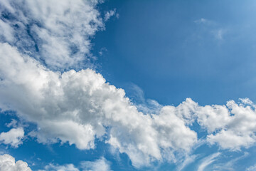 White clouds scattered around a vivid blue sky forming a circular opening that creates a dynamic...