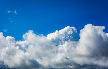 Massive white clouds rising against a bright blue sky creating a dramatic and atmospheric...