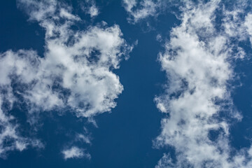 White clouds scattered around a vivid blue sky forming a circular opening that creates a dynamic...