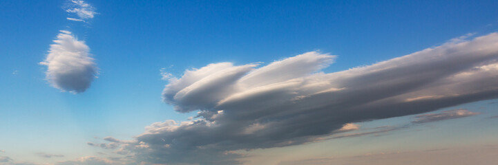Massive white clouds hovering above a blue sea and sky horizon creating a dynamic weather scene...