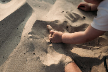 Young girl playing and drawing in the sand with a stick on the beach at golden hour. A tender, warm moment of summer.