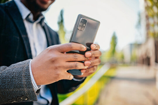 Young black businessman uses smartphone outdoors in an urban setting during daylight hours