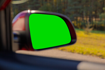 view in the rear view side mirror of a auto, driving a red car along the road