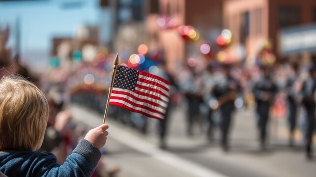 Close-up of a child holding a small American flag at a Memorial Day parade, blurred background with marching veterans and red, white, and blue decorations
