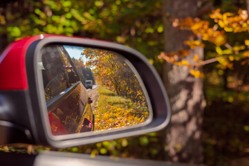 The sun is reflected in the mirror, evening road. View in the rear view side mirror of a auto,...