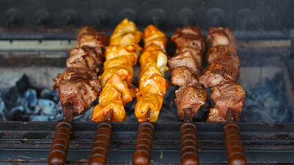Skewered meat sizzling over automatic charcoal grill on summer day