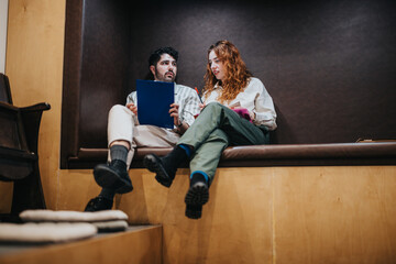 Two colleagues engaged in discussion during a collaborative work session in a cozy modern interior,...