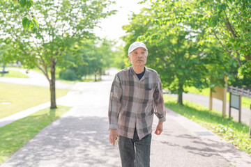 In a lush green park on a sunny May day, a Japanese man in his late 70s stands alone. Wearing a...