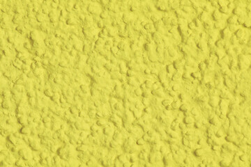 The wall is yellow and has a bumpy texture. It is not smooth and has a rough surface