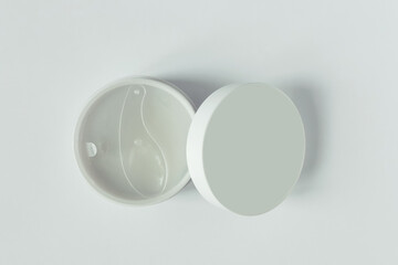 White open jar with cosmetic product and hygienic plastic spoon dispenser. White background.